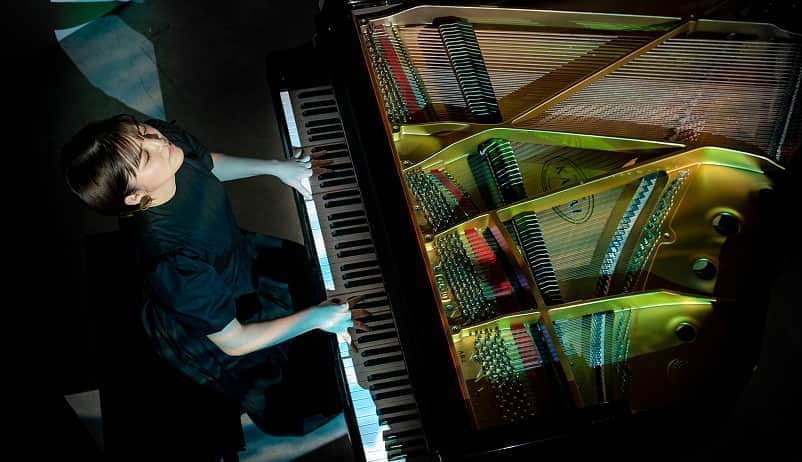 上を向いてピアノを弾いている女性