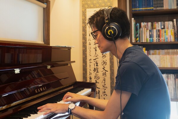 消音機能のヘッドホンを着けて演奏しているご主人